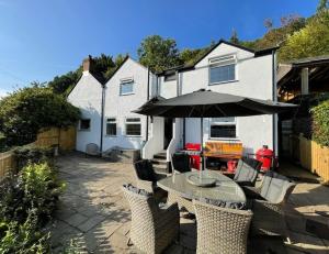 a patio with a table and an umbrella at Crossways Cottage - Symonds Yat in Symonds Yat