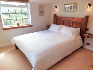 a bedroom with a large white bed with a window at Crossways Cottage - Symonds Yat in Symonds Yat