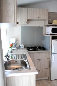 cocina con fregadero y fogones en Camping Resort Les Champs Blancs en Agde