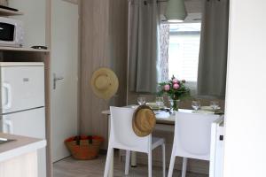 una cucina con tavolo bianco e sedie bianche di Camping Resort Les Champs Blancs ad Agde