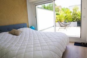 a bedroom with a large white bed and a patio at EXIGEHOME- Maison d'architecte avec SPA - V2 in Orgeval