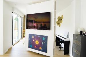 ein Wohnzimmer mit einem Klavier und einem Flachbild-TV in der Unterkunft EXIGEHOME- Maison d'architecte avec SPA - V2 in Orgeval