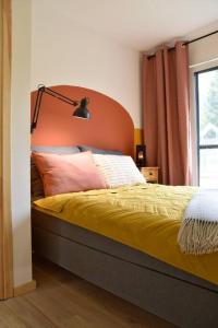 a bed with an orange headboard in a bedroom at Żywiołowo - domki w stylu stodoły z placem zabaw i stawem - OGIEŃ in Parchowo