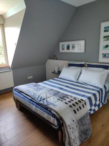 a bedroom with a bed with a blue and white blanket at La Hautée des Francs in Veigné