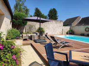 - une terrasse avec des chaises et un parasol à côté de la piscine dans l'établissement La Hautée des Francs, à Veigné