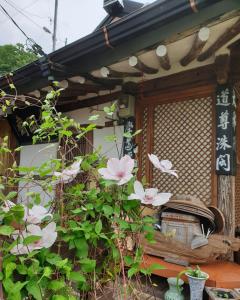 dom z różowymi kwiatami przed nim w obiekcie Gugangjae Hanok Stay w mieście Jeonju