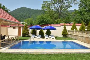 a swimming pool with two umbrellas and chairs at Foothills Villa in Gabala