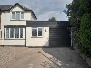 a garage with a black garage door on a house at One bed stunning apartment with parking right outside, close to Burton town centre in Burton upon Trent