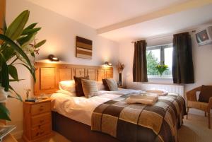 a bedroom with a large bed with a wooden headboard at Sladen Lodge in Hathersage