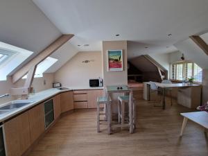an attic kitchen with wooden cabinets and stools at Gite -l'Appart- au Vignoble Domaine Lamballe, Baden, Golfe du Morbihan in Baden
