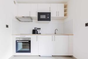 eine Küche mit weißen Schränken und einer Mikrowelle in der Unterkunft Charming Studio - 2P- La DéfensePuteaux in Puteaux