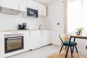 eine Küche mit weißen Schränken und einem Tisch in der Unterkunft Charming Studio - 2P- La DéfensePuteaux in Puteaux