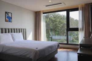 a bedroom with a bed and a large window at Hotel Seogwipean in Seogwipo
