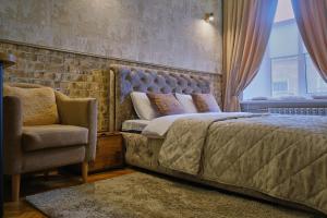 a bedroom with a bed and a chair and a window at Central Apartments in Odesa