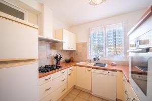 eine Küche mit weißen Schränken und einem Herd mit Backofen in der Unterkunft Une Maison à la Mer - Proche de la marina in Saint-Cyprien + 8 Fotos