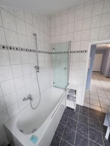 y baño blanco con bañera y ducha. en Ruhiges Juwel: frisch renoviert 100 qm, en Julich