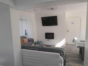 a living room with a couch and a tv on the wall at One bed stunning apartment with parking right outside, close to Burton town centre in Burton upon Trent