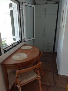 cocina con mesa, silla y ventana en Nostalgia Guesthouse, en Skoutari