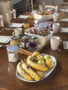 einem Holztisch mit einem Teller Bananen und Äpfel in der Unterkunft LAURAGUEL CHAMBRES D'HÔTES in Mourvilles-Hautes