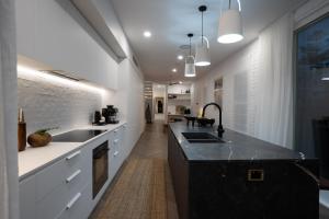 una cocina con armarios blancos y encimeras negras en The Manly House - 100 steps from Manly Beach en Sídney