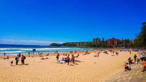 a large group of people on a beach at The Manly House - 100 steps from Manly Beach in Sydney