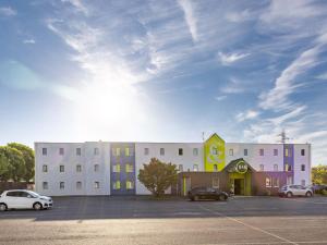 un edificio bianco con auto parcheggiate in un parcheggio di B&B HOTEL Rennes Est Cesson Sévigné a Cesson-Sévigné