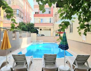 a swimming pool with chairs and an umbrella at Kleopatra Sahara Hotel in Alanya