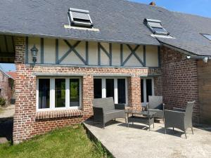 a brick house with chairs and a table and windows at Le Clos Charmaine in Auquemesnil