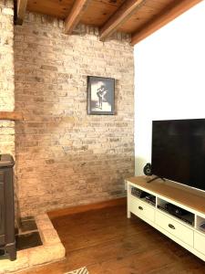 ein Wohnzimmer mit einem TV an einer Backsteinwand in der Unterkunft De Scheure, charmant vakantiehuisje midden in de natuur in Alveringem