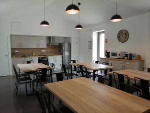 una cocina con mesas y sillas de madera y un reloj en la pared en LA BORDERIE - MAISON DES RANDONNEES - Gîte étape - gîte de groupe en Vairé