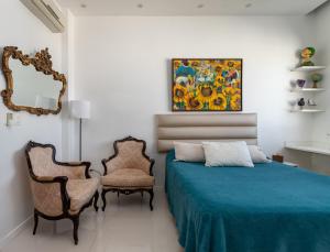 1 dormitorio con 1 cama, 2 sillas y una pintura en Loft Catete, en Río de Janeiro