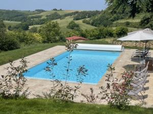 a swimming pool in a yard with an umbrella at LAURAGUEL CHAMBRES D'HÔTES in Mourvilles-Hautes