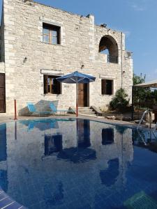 une piscine avec un parasol et des chaises et un bâtiment dans l'établissement Hephaestus Villa, à Kapparianá