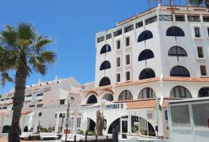 un alto edificio bianco con una palma di fronte di ZioCarlo/Las Americas a Playa de las Americas