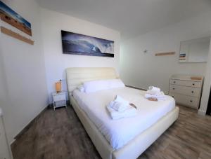 una camera da letto con un letto bianco con due asciugamani di ZioCarlo/Las Americas a Playa de las Americas