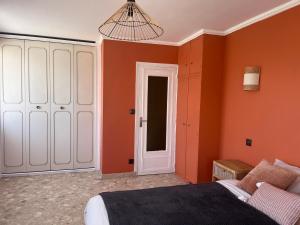 - une chambre avec des murs orange, un lit et un lustre dans l'établissement Maison spacieuse et autonome au centre-ville de Tournus, à Tournus
