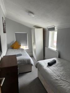 a small room with two beds and a desk and a table at Eva Suites in Gillingham