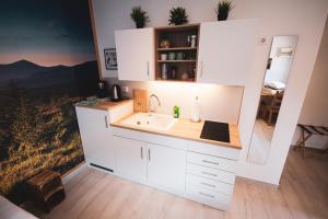 a kitchen with white cabinets and a sink at Northwest Studio Apartments in Klagenfurt