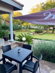 a patio with a table and chairs and an umbrella at Moments Guest House in Klerksdorp