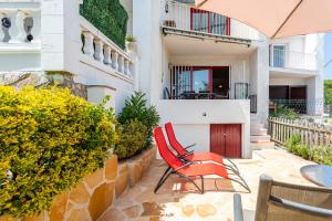 a pair of red chairs sitting on a patio at Cosy Holiday Cottage in Tossa de Mar