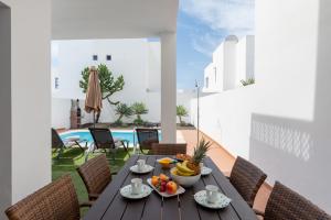 a table with fruit on a balcony with a pool at Luxury 3-bedroom villa with private pool in Marina Rubicon, Playa Blanca, Lanzarote in Playa Blanca