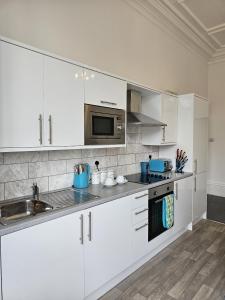 a kitchen with white cabinets and a sink and a microwave at Edgerton Studios in Huddersfield