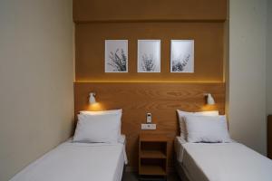 two beds in a room with three pictures on the wall at No 22 Riders' Inn in Akyaka