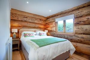 Schlafzimmer mit Holzwänden, einem Bett und einem Fenster in der Unterkunft Frankaborough Lodge in Virginstow