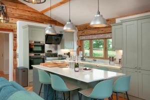 a kitchen with a large white island with blue chairs at Frankaborough Lodge in Virginstow