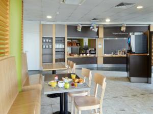a restaurant with a table and chairs and a kitchen at B&B HOTEL Paris Roissy CDG Aéroport in Roissy-en-France