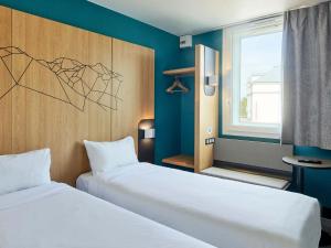 a room with two beds and a window at B&B HOTEL Paris Roissy CDG A&eacute;roport in Roissy-en-France