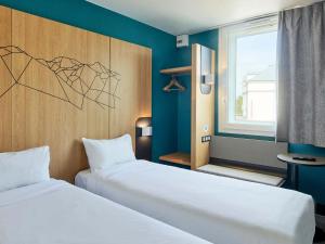 a room with two beds and a window at B&B HOTEL Paris Roissy CDG Aéroport in Roissy-en-France
