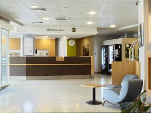 a waiting room with a chair and a counter at B&B HOTEL Paris Roissy CDG Aéroport in Roissy-en-France