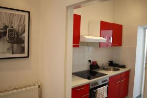 Elle comprend une petite cuisine avec des placards rouges et un évier. dans l'établissement BLOOM - Cozy Apartment, 5 stops to City Center, à Vienne